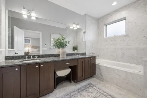 a bathroom with a granite countertop bathtub a sink and a large mirror