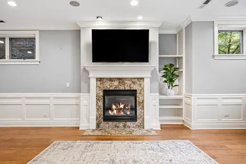 a living room with a fireplace a flat screen tv and a potted plant