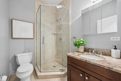 a bathroom with a granite countertop sink a toilet and shower