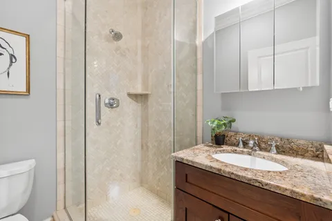 a bathroom with a granite countertop sink a toilet and shower
