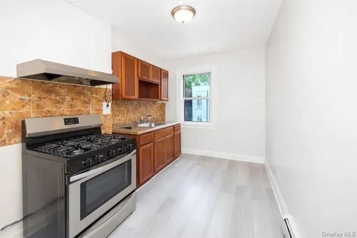 88-08 88th Street Queens, NY 11421 - Photo 32 of 32 a kitchen with stainless steel appliances a stove a sink and a microwave