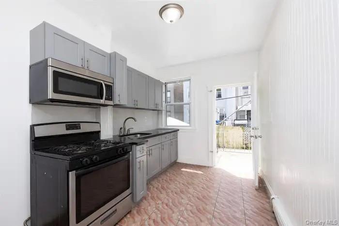 88-08 88th Street Queens, NY 11421 - Photo 6 of 32 a kitchen with granite countertop a stove and a microwave