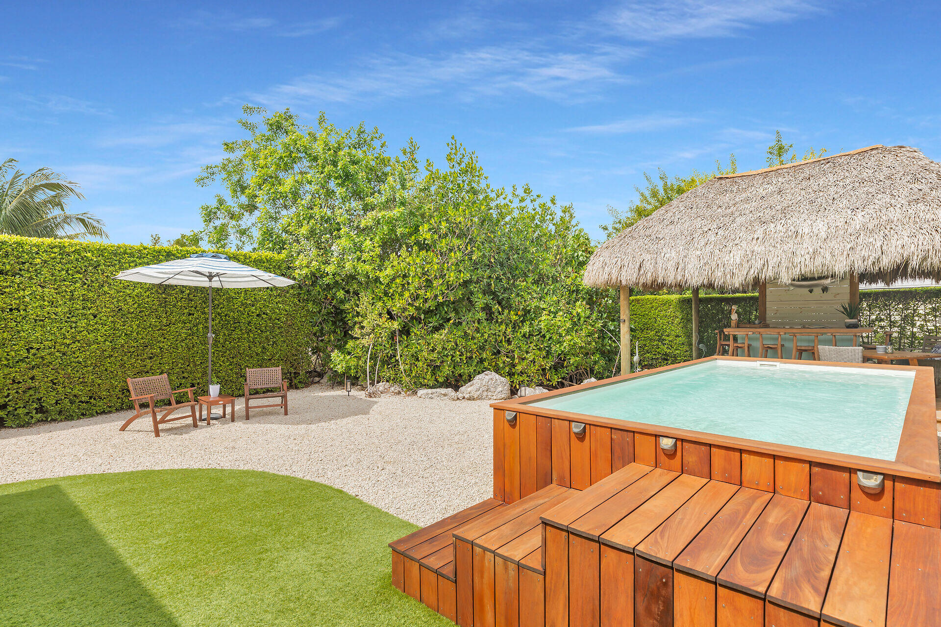 553 Oldsmar Lane Key Largo, FL 33037 - Photo 11 of 48 a view of a swimming pool with a table and chairs under an umbrella