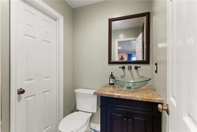 a bathroom with a granite countertop sink toilet and mirror