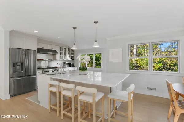 a kitchen with stainless steel appliances granite countertop a refrigerator a sink a stove a dining table and chairs