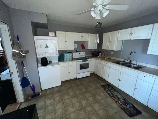 a kitchen with a sink a stove cabinets and white appliances
