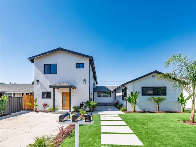 a front view of a house with a yard and potted plants