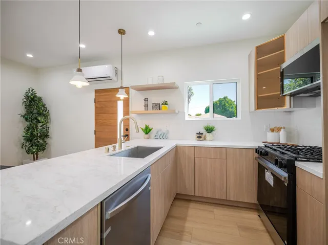 a kitchen with stainless steel appliances granite countertop a sink a stove and a wooden floors