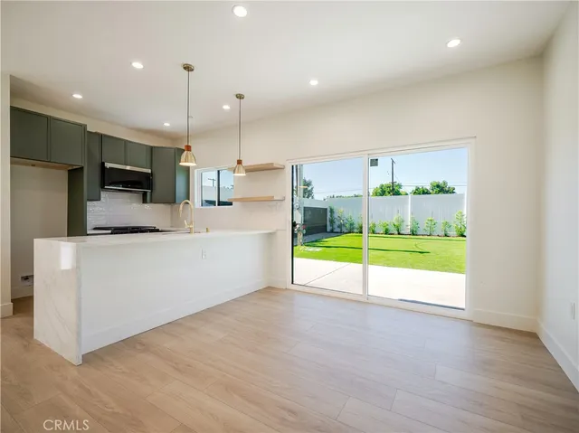 a view of a kitchen with kitchen island a stove a refrigerator and a view of living room