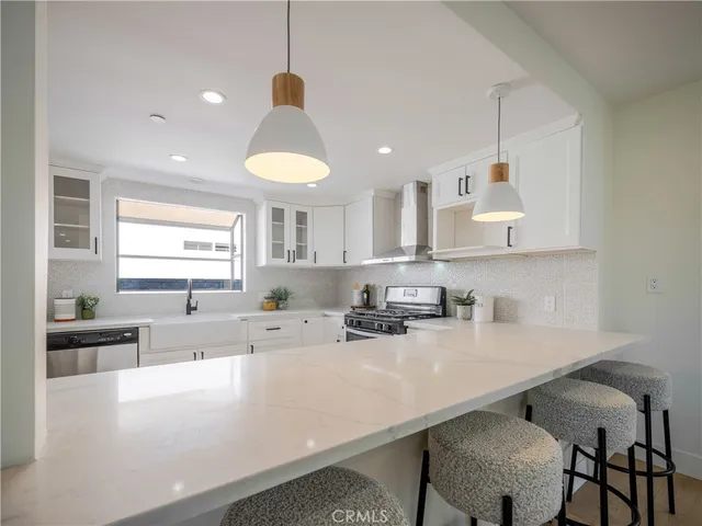 a kitchen with stainless steel appliances a sink a stove a refrigerator a center island and furniture