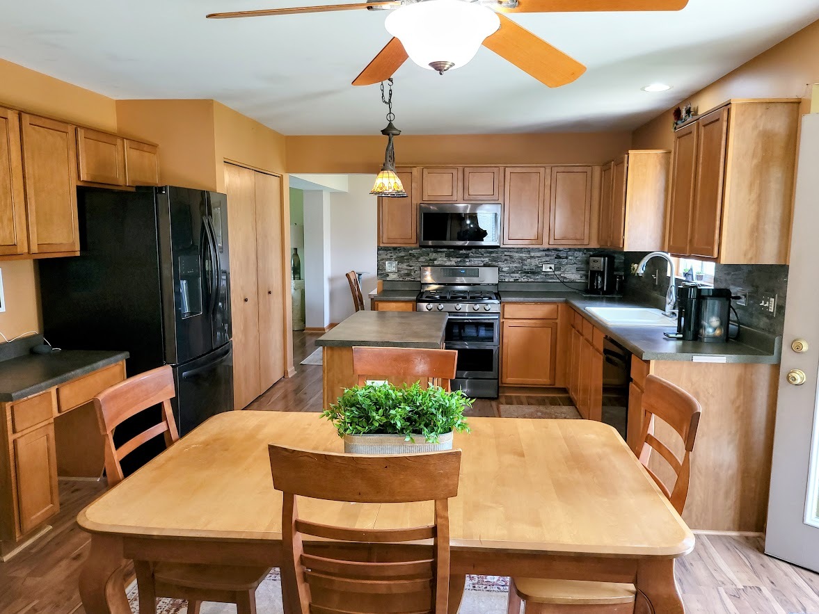 156 Sycamore Drive Bolingbrook, IL 60490 - Photo 7 of 26 a kitchen with stainless steel appliances granite countertop a stove refrigerator a sink dishwasher a dining table and chairs with wooden floor