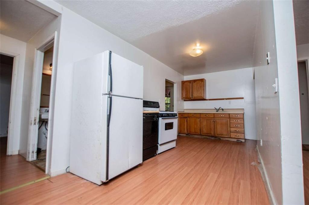 7104 Miller Street Lithia Springs, GA 30122 - Photo 14 of 18 a kitchen with a refrigerator a stove top oven and wooden floor