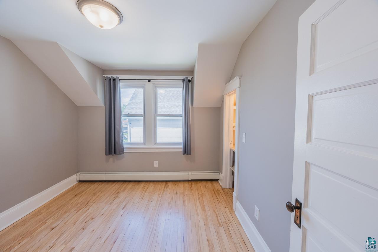 508 10th Street South Virginia, MN 55792 - Photo 19 of 43 Bright room featuring wood-finish flooring, a double window, baseboard heating, a contemporary flush-mount ceiling light, and a paneled door