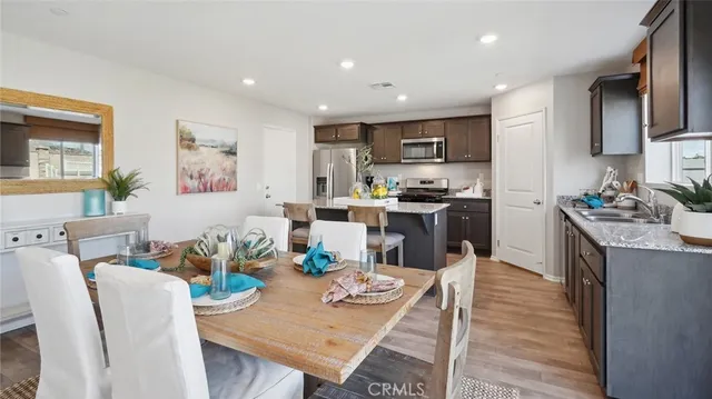 a kitchen with stainless steel appliances kitchen island granite countertop a table chairs and a refrigerator