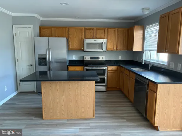 a kitchen with stainless steel appliances granite countertop a stove a sink dishwasher a microwave oven and a refrigerator with wooden floor