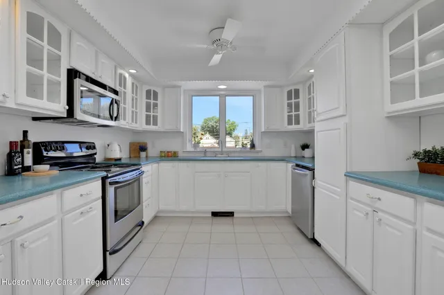 a kitchen with white cabinets and window