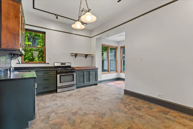 a view of an empty room with a window and a kitchen