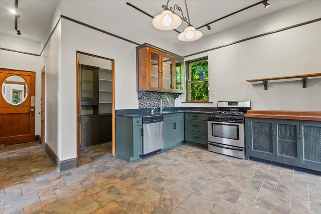 a view of an empty room with a window and kitchen view