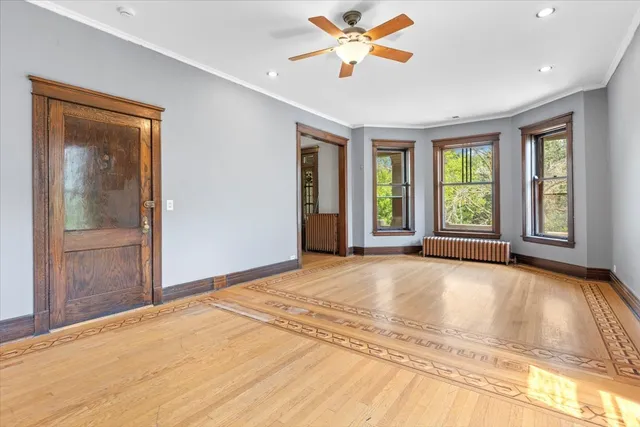 a view of an empty room with a window and wooden floor