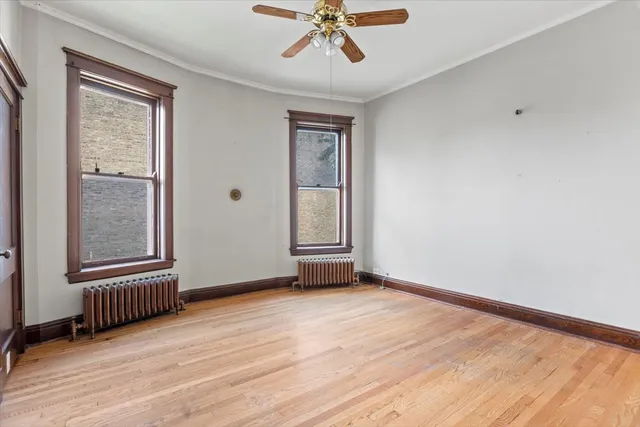 an empty room with windows a fireplace a ceiling fan and wooden floor
