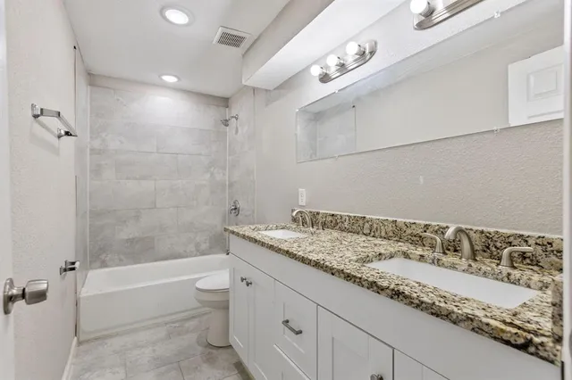 a bathroom with a granite countertop sink a toilet and bathtub