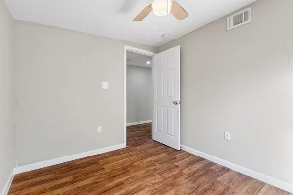an empty room with wooden floor and ceiling fan