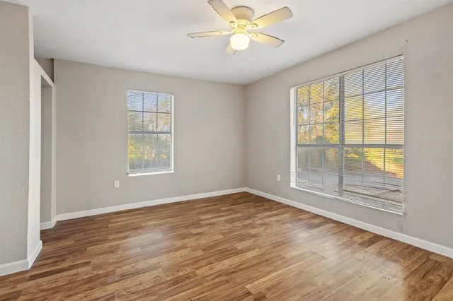 a view of an empty room with a window and wooden floor