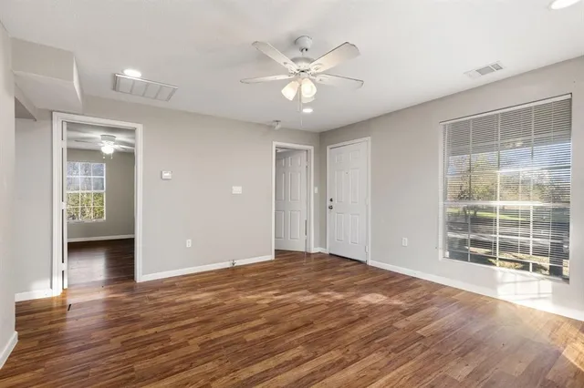 a view of an empty room with a window and wooden floor