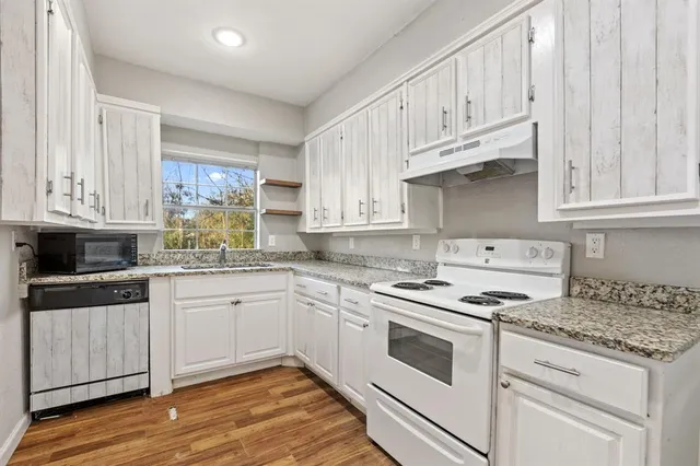 a kitchen with granite countertop white cabinets and white appliances