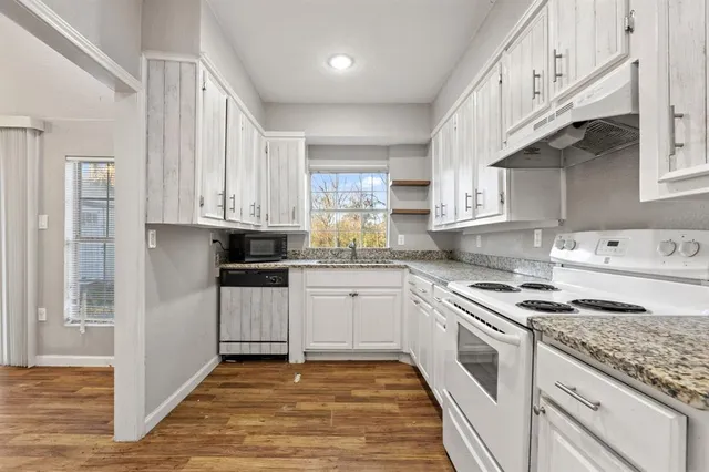 a kitchen with granite countertop white cabinets and white appliances