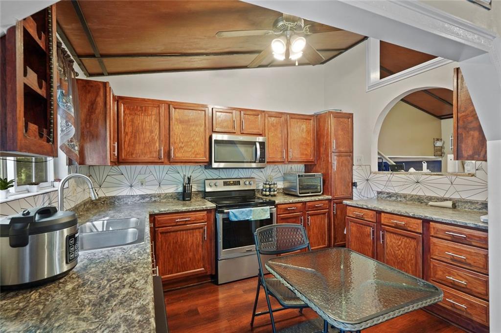 884 Forest Path Stone Mountain, GA 30088 - Photo 10 of 24 a kitchen with stainless steel appliances granite countertop a stove top oven a sink dishwasher a dining table and chairs with wooden floor