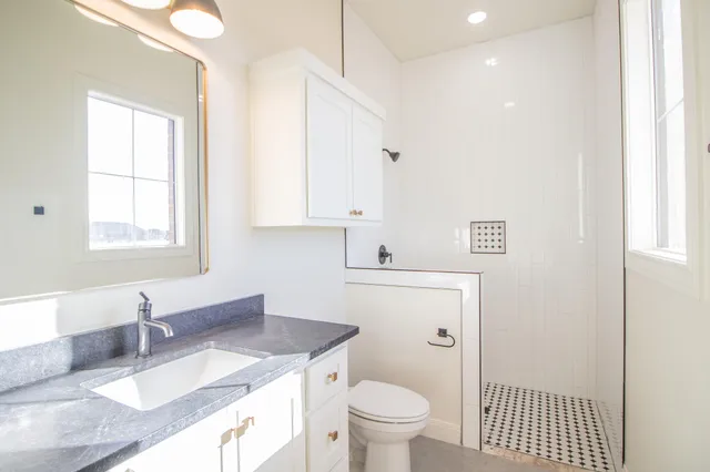 a bathroom with a granite countertop sink mirror vanity and toilet