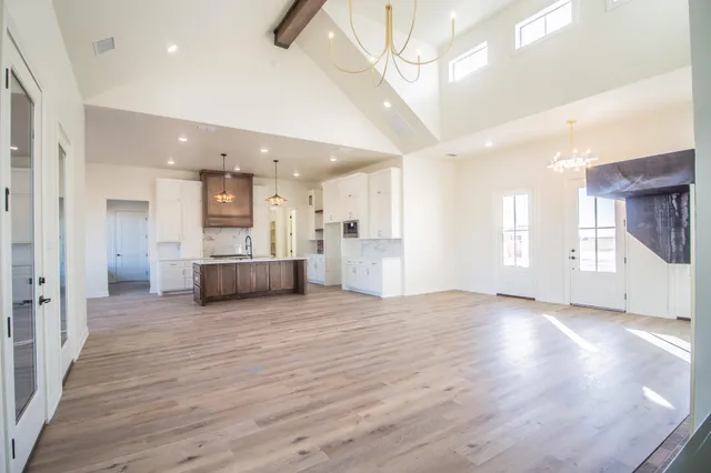 a view of a big room with wooden floor and a kitchen
