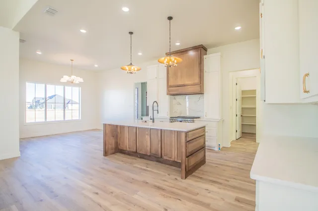 a large kitchen with kitchen island a stove a sink a refrigerator and wooden floor