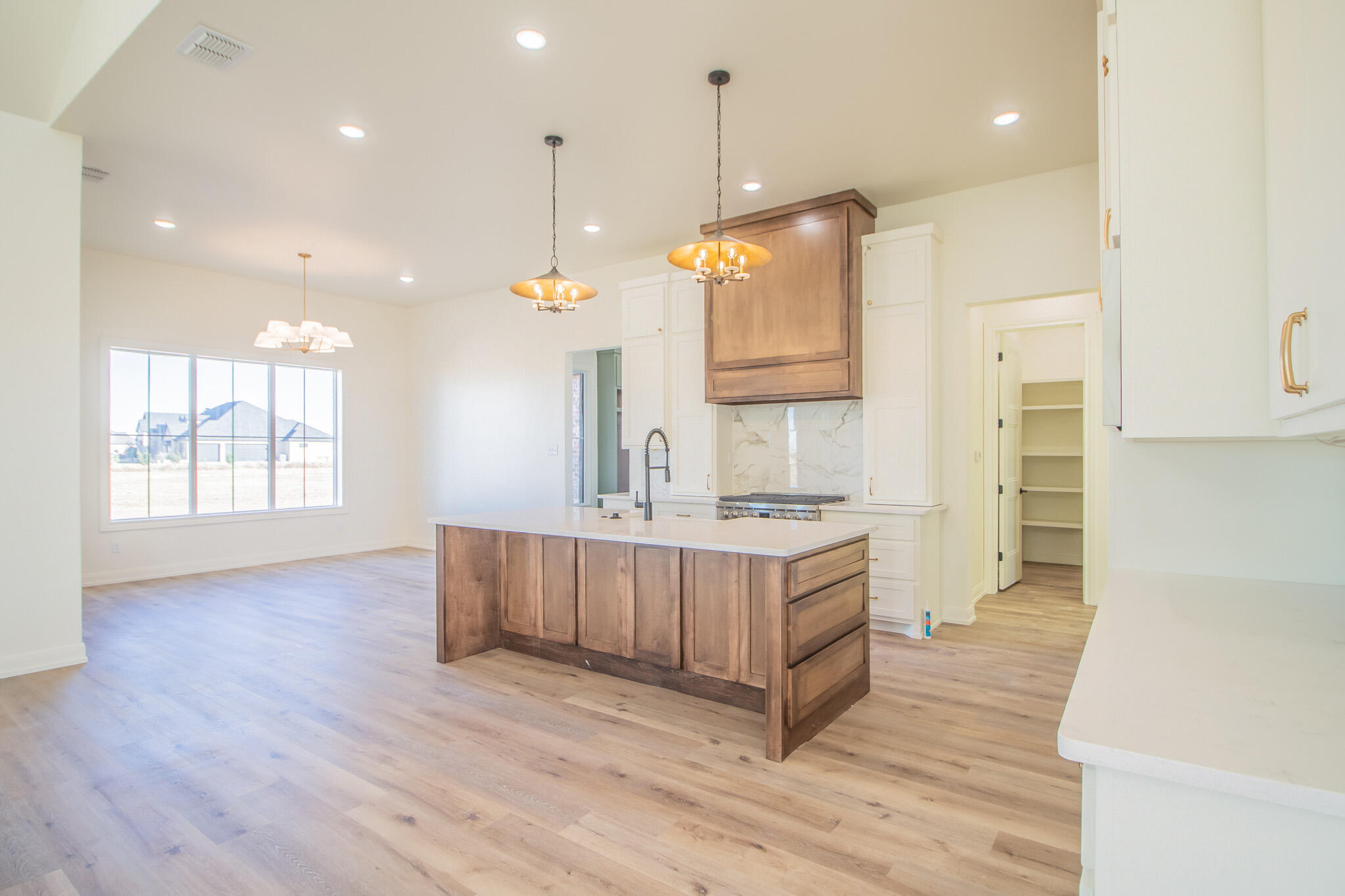 303 Juniper New Home, TX 79381 - Photo 8 of 31 a large kitchen with kitchen island a stove a sink a refrigerator and wooden floor