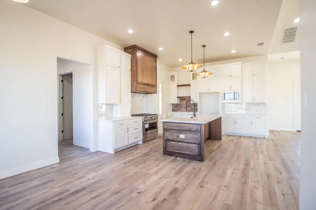 a large kitchen with kitchen island white cabinets and stainless steel appliances