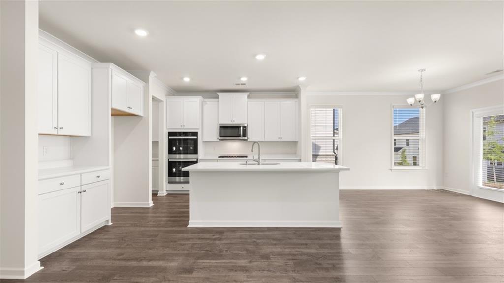 1779 Goodwin Drive Hampton, GA 30228 - Photo 5 of 49 a kitchen with stainless steel appliances kitchen island granite countertop a stove a sink a refrigerator and white cabinets with wooden floor