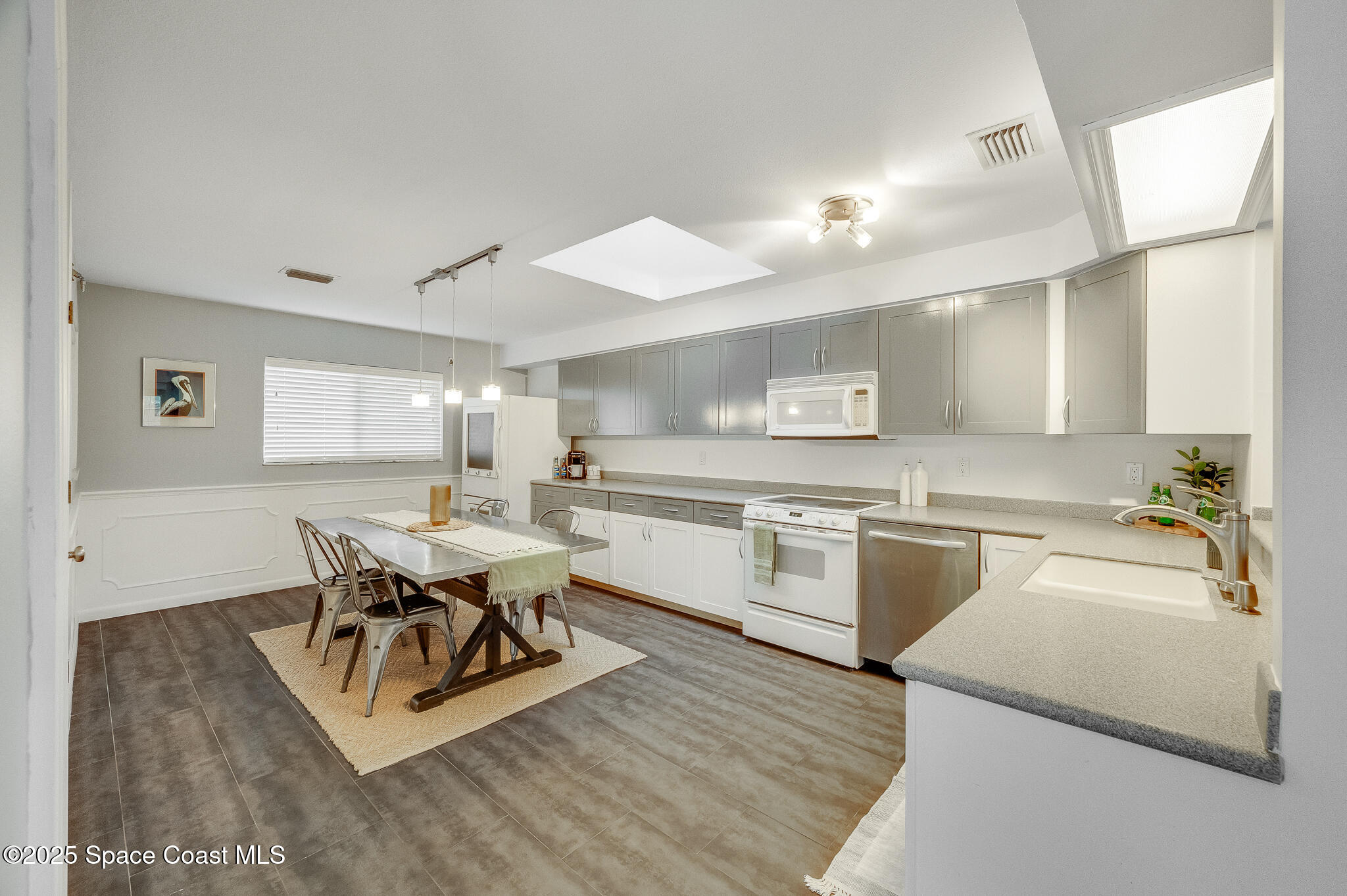 3319 Kirkland Road Northeast Palm Bay, FL 32905 - Photo 2 of 50 a large white kitchen with a stove a sink a refrigerator and a dining table with wooden floor