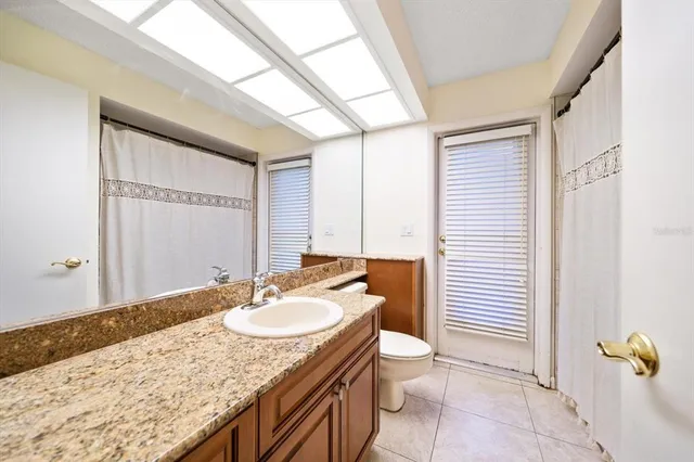 a bathroom with a granite countertop sink a toilet and mirror
