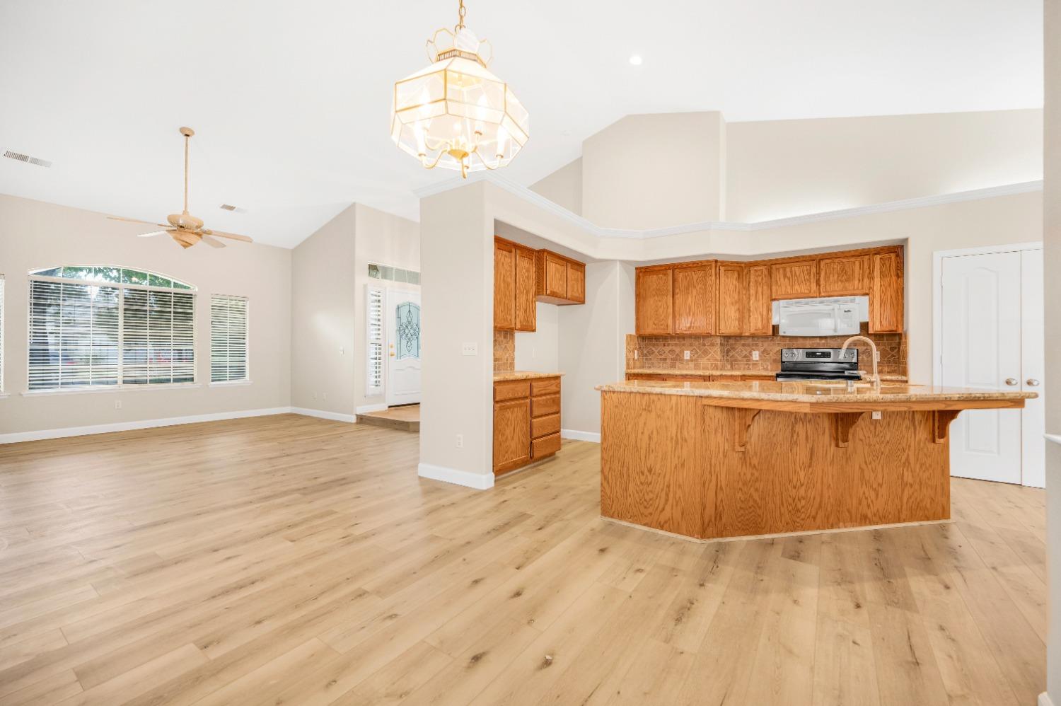 733 Applegate Avenue Clovis, CA 93611 - Photo 6 of 25 a view of a kitchen with kitchen island granite countertop wooden floor and stainless steel appliances