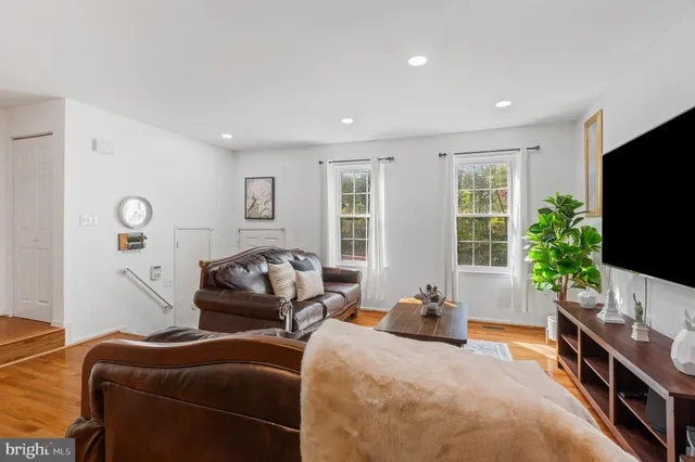 a living room with furniture kitchen view and a wooden floor