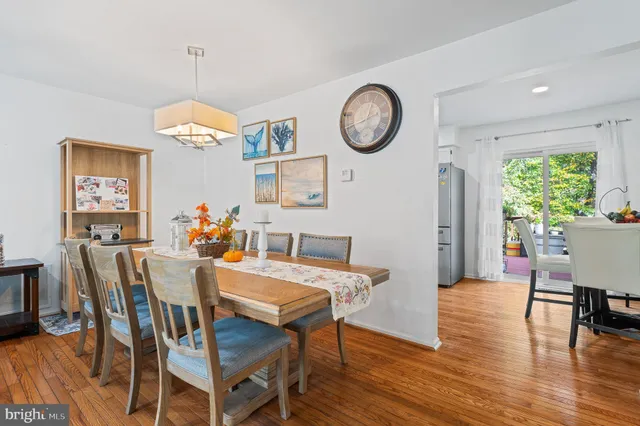 a living room with stainless steel appliances furniture dining table and wooden floor