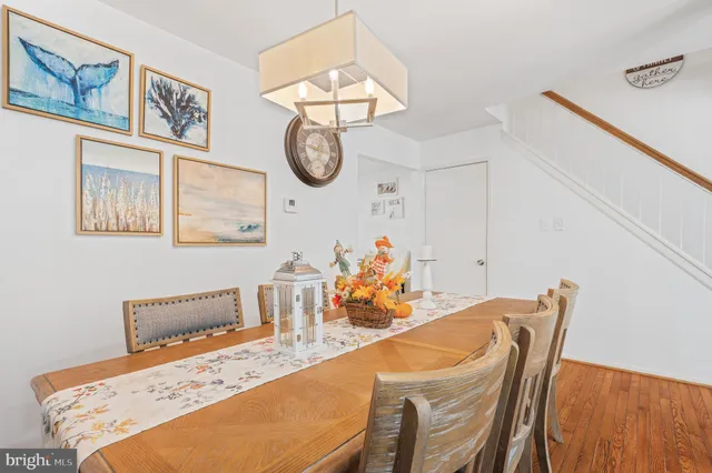 a kitchen with stainless steel appliances a refrigerator a stove a sink dishwasher a dining table and chairs with wooden floor