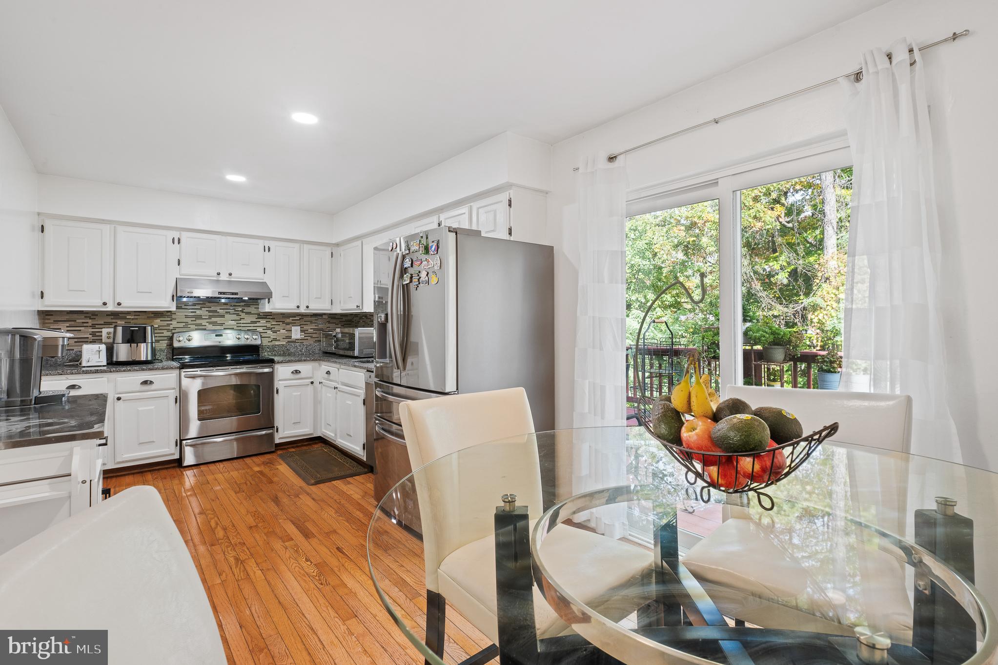 13007 Climbing Ivy Drive Germantown, MD 20874 - Photo 28 of 63 a kitchen with stainless steel appliances a refrigerator a stove a sink dishwasher a dining table and chairs with wooden floor