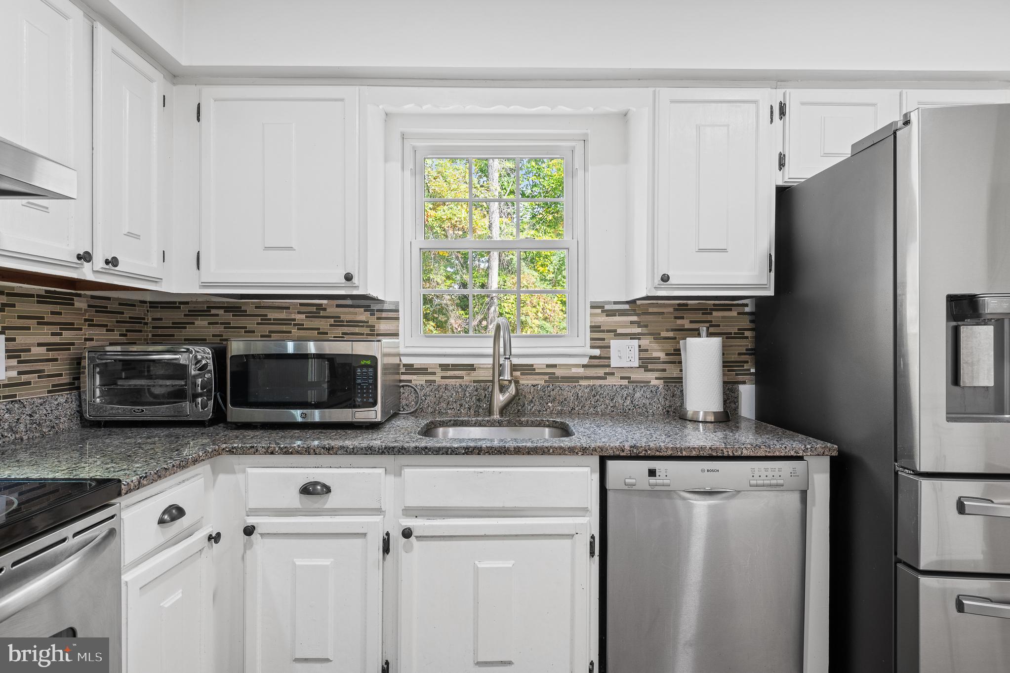 13007 Climbing Ivy Drive Germantown, MD 20874 - Photo 32 of 63 a kitchen with granite countertop white cabinets white stainless steel appliances and a refrigerator