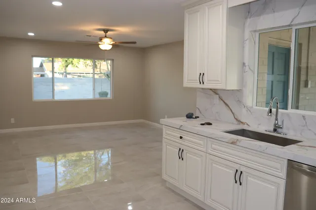 a kitchen with white cabinets and window