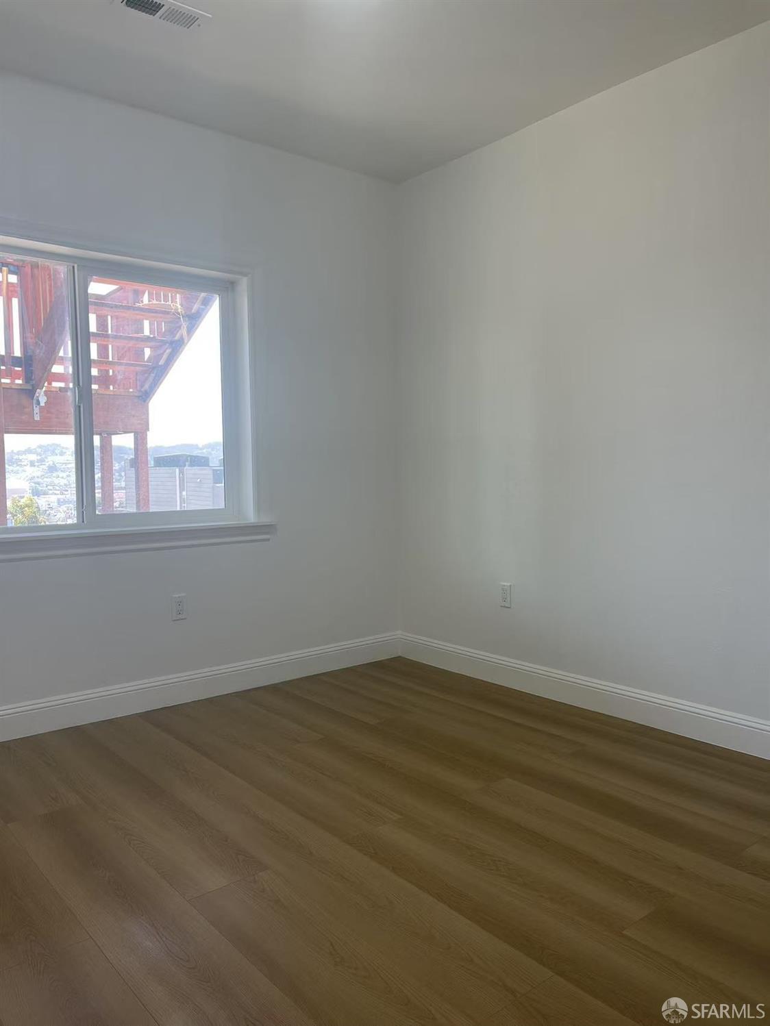1435 Newcomb Avenue San Francisco, CA 94124 - Photo 6 of 9 a view of an empty room with wooden floor and a window
