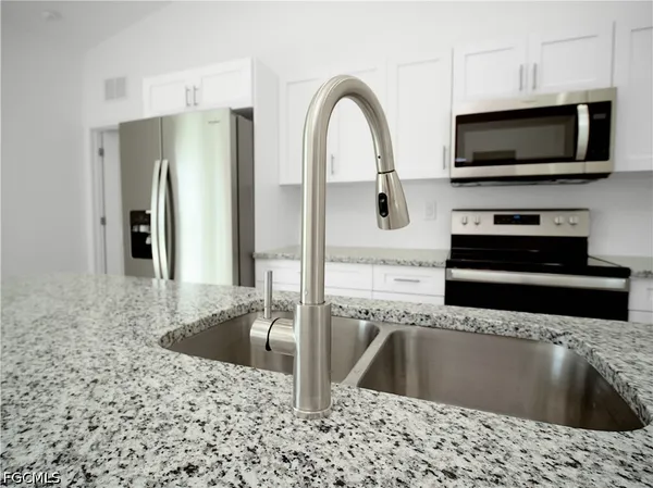 a kitchen with stainless steel appliances kitchen island a refrigerator sink and microwave