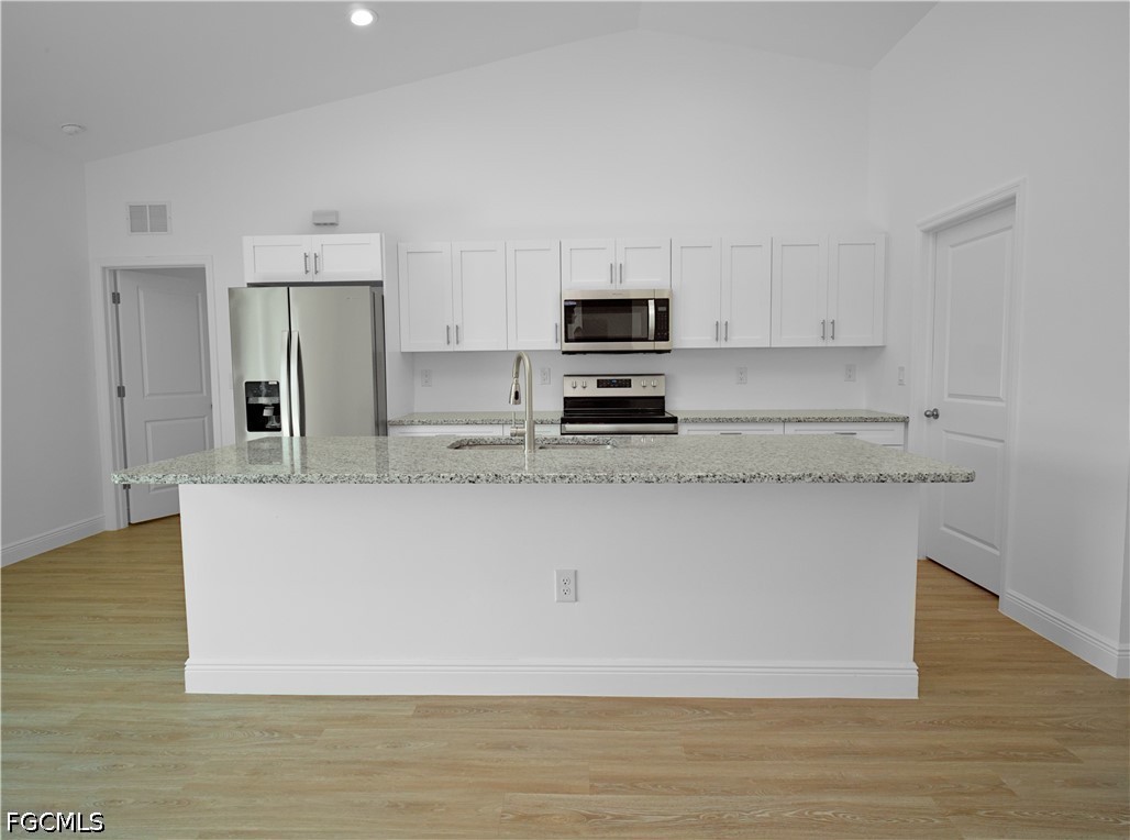 5021 Myrtlewood Road LaBelle, FL 33935 - Photo 7 of 10 a large white kitchen with kitchen island a stove a sink and a refrigerator