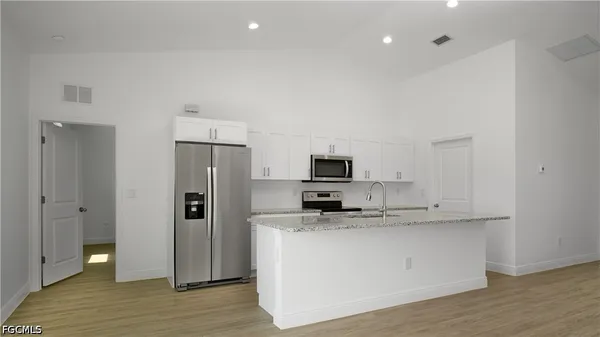 a large kitchen with stainless steel appliances a refrigerator a stove a sink and a stove with wooden floor